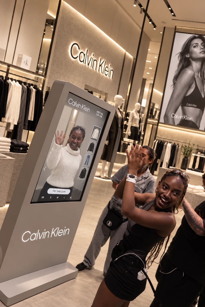 Participante sorrindo e interagindo com um totem Calvin Klein